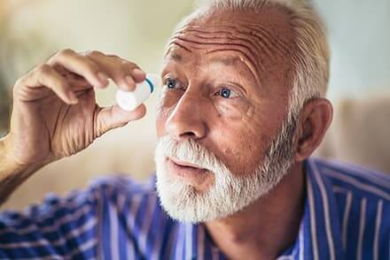 older man putting in eye drops